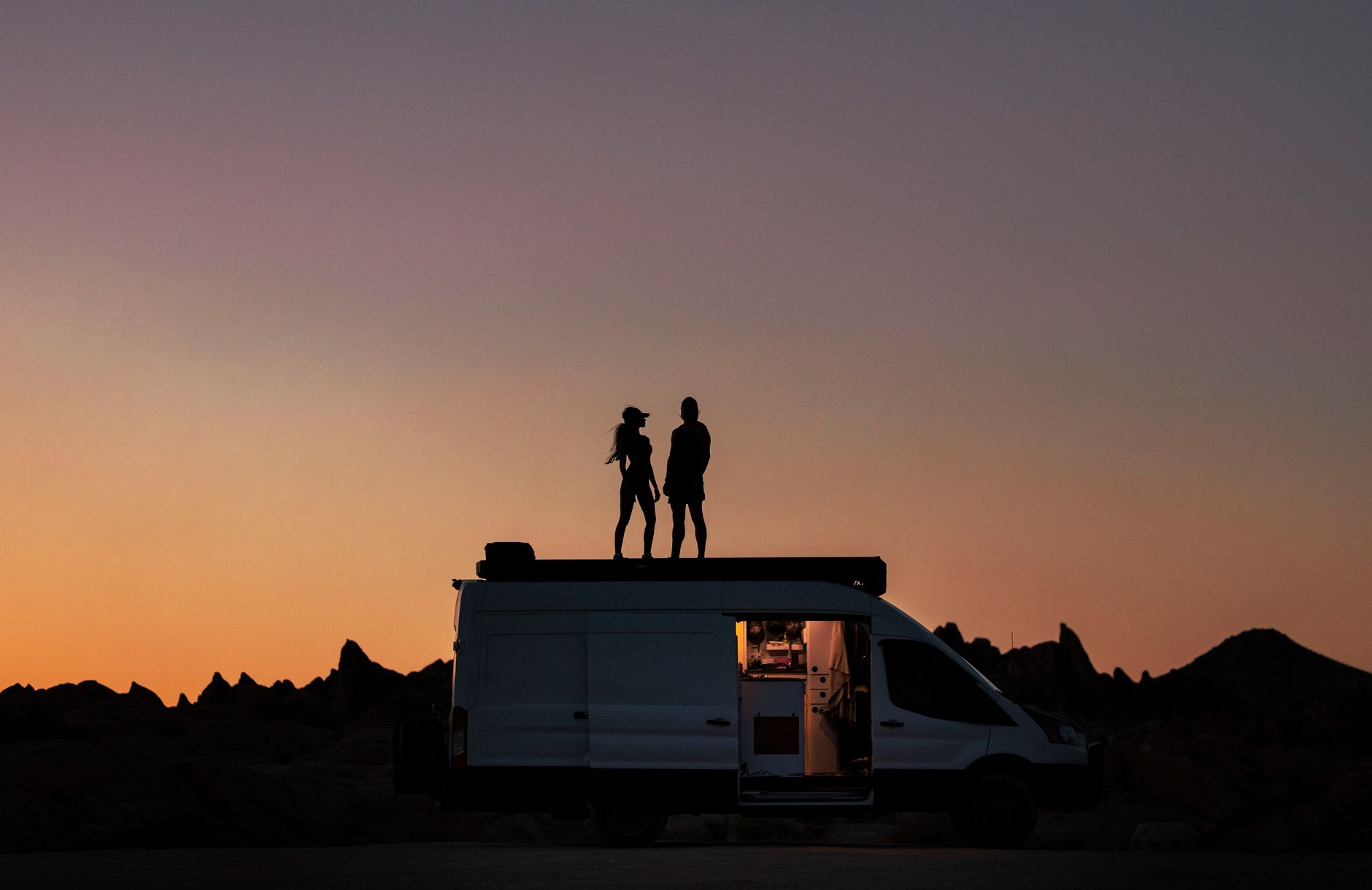 silhouette of couple on a van during sunset